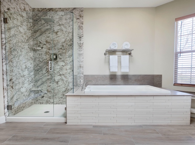 A bathroom with a glass shower and bathtub
Description automatically generated