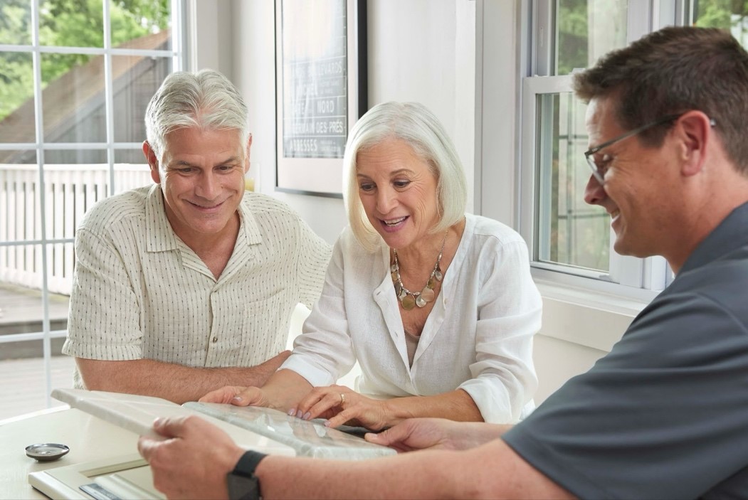 An older man and woman sit across from a male Re-Bath employee discussing opportunities for their franchise. | Re-Bath