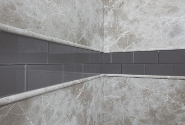 Gray marble wall tiles with a horizontal strip of dark rectangular accent tiles. | Re-Bath Franchising