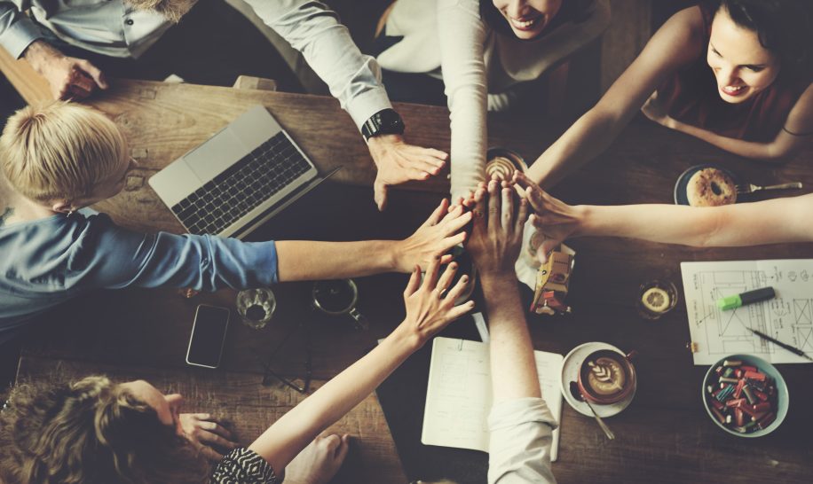 Group of people raising hands together